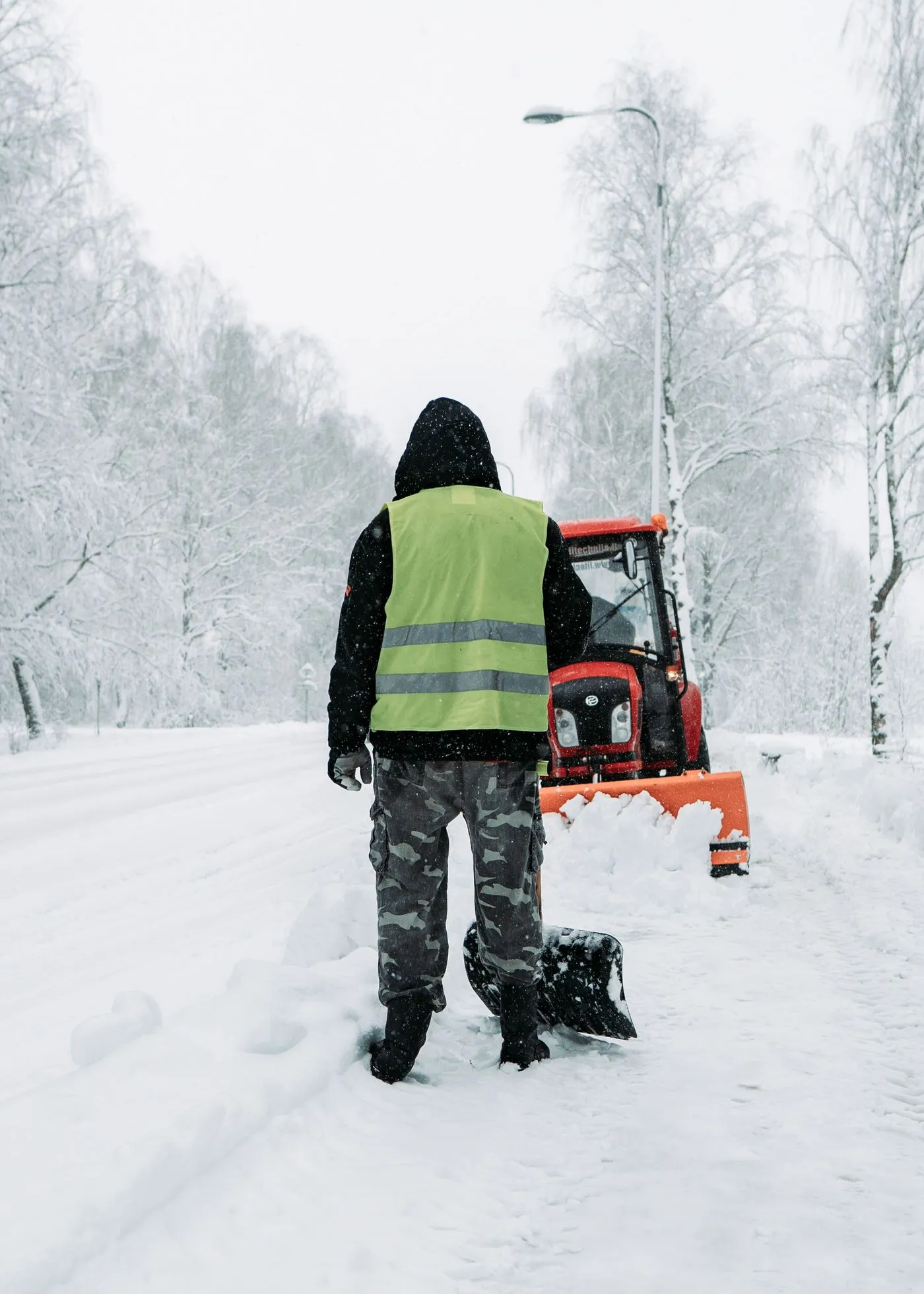 A worker in a vest clearing snow, standing in for the Milwaukee M12 Heated AXIS Vest