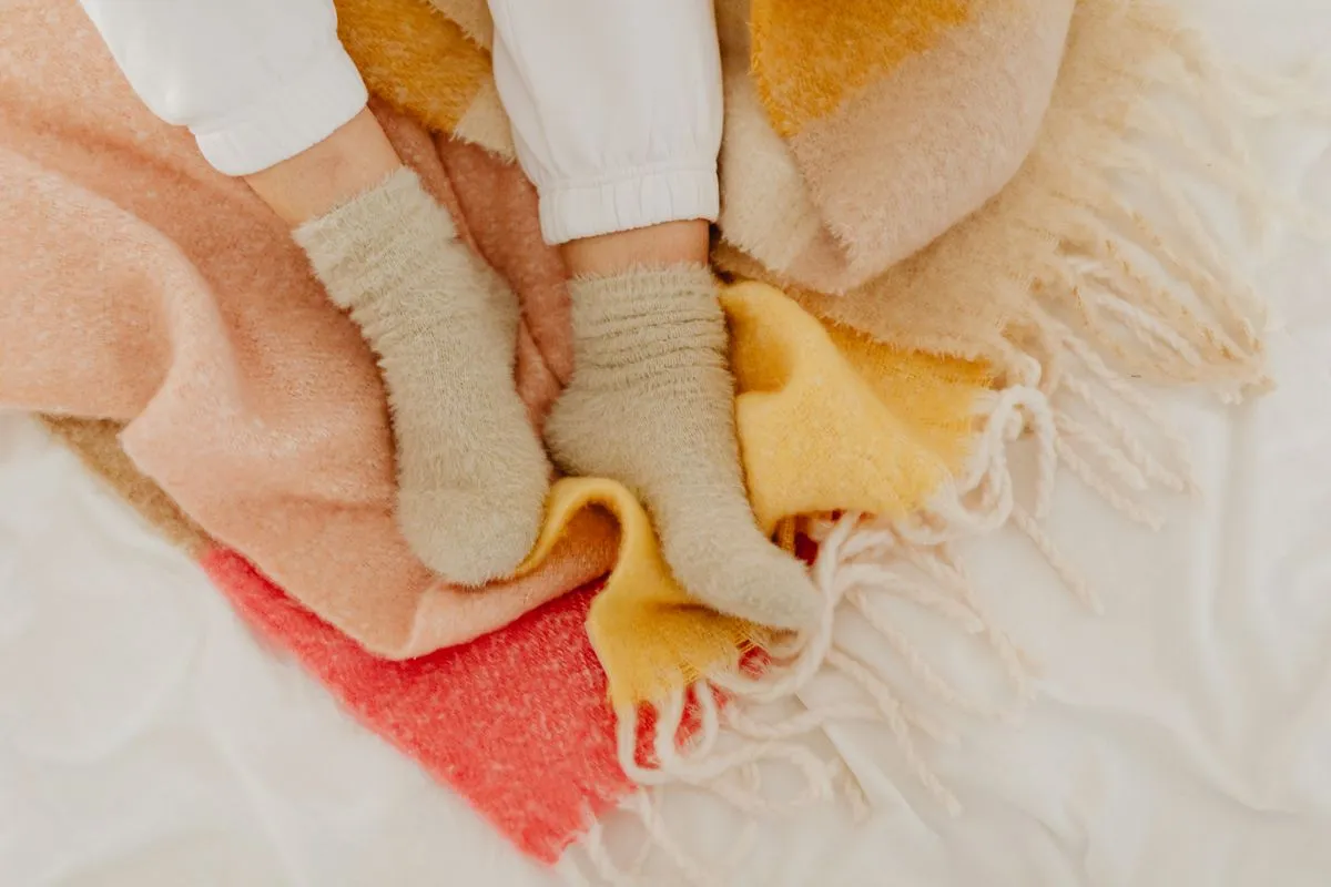 Wool socks on a knit blanket, standing in for the Driftpeak Wool Heat Socks