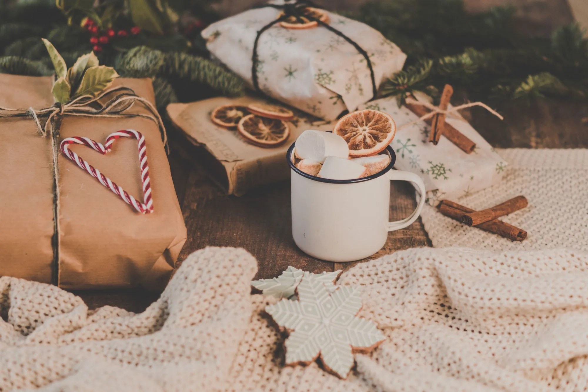 Wrapped presents, a mug of hot chocolate and a knit blanket on a table