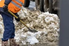A worker in a high-visibility vest clearing snow, standing in for the Kestrel Work Heated Jacket