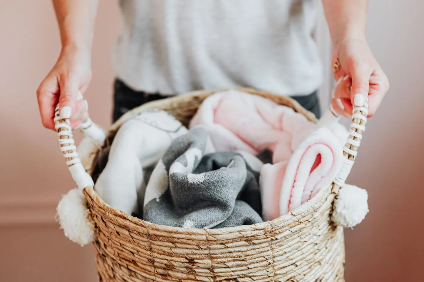 Hands holding a woven basket of soft rolled blankets