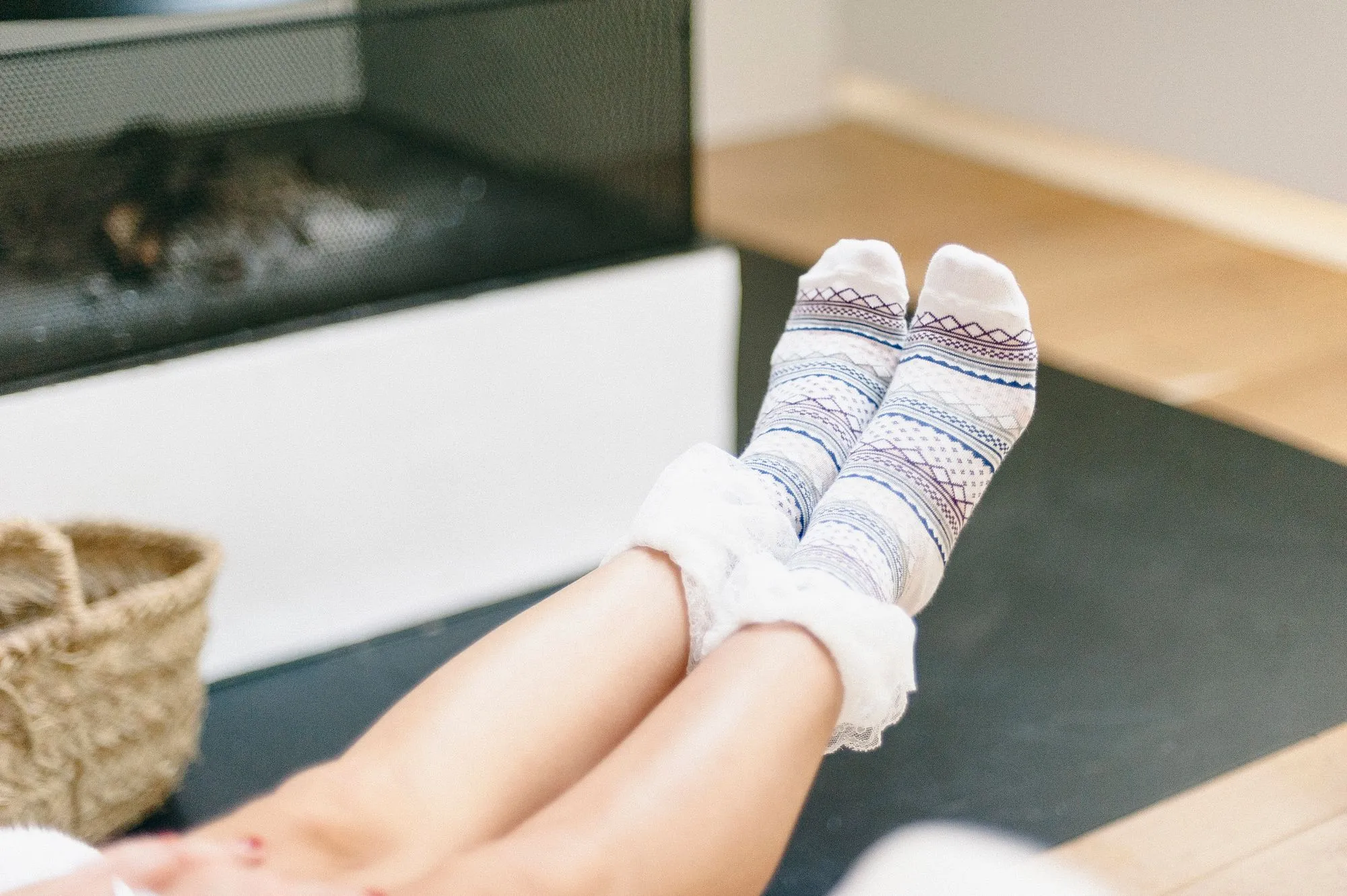 Feet in wool socks by a fireplace, standing in for the Lumen Merino Heated Socks