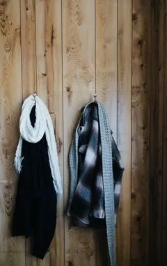 Knit scarves hanging on hooks, standing in for the Ember Loop Heated Scarf