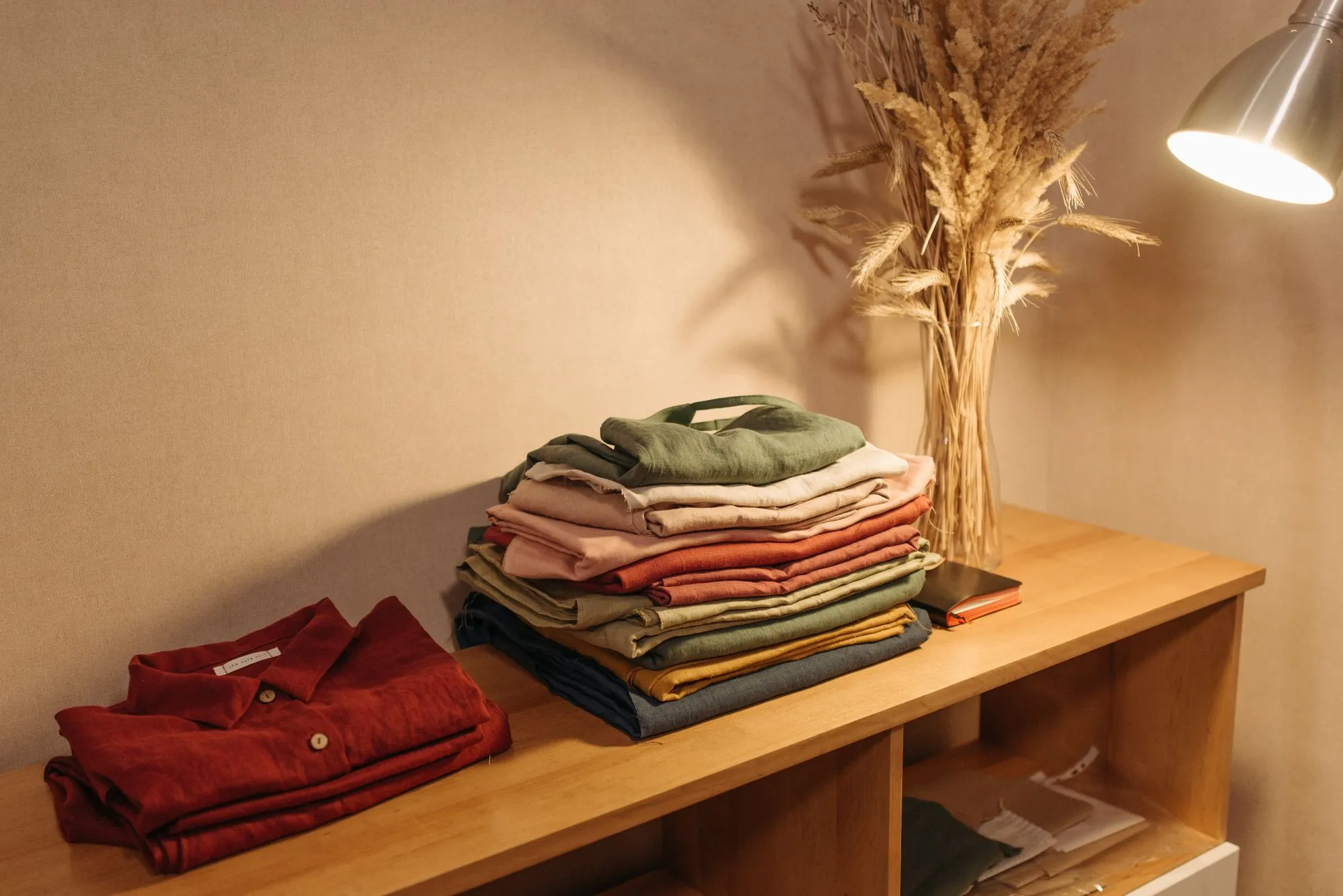 Folded winter clothes on a wooden cabinet under a warm lamp